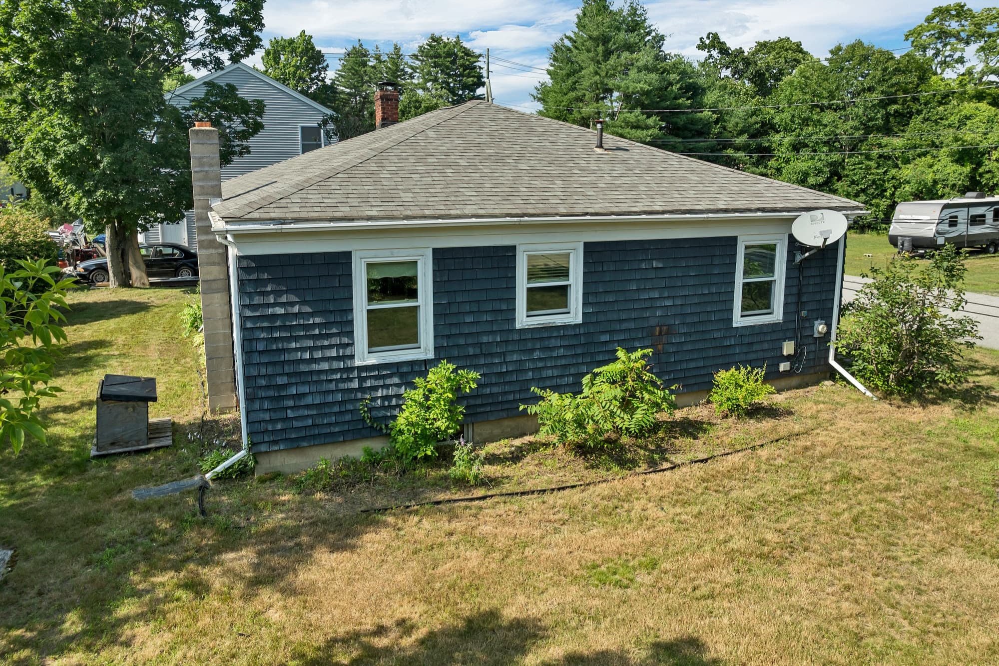 Rear elevation of the home with the lawn and mature trees