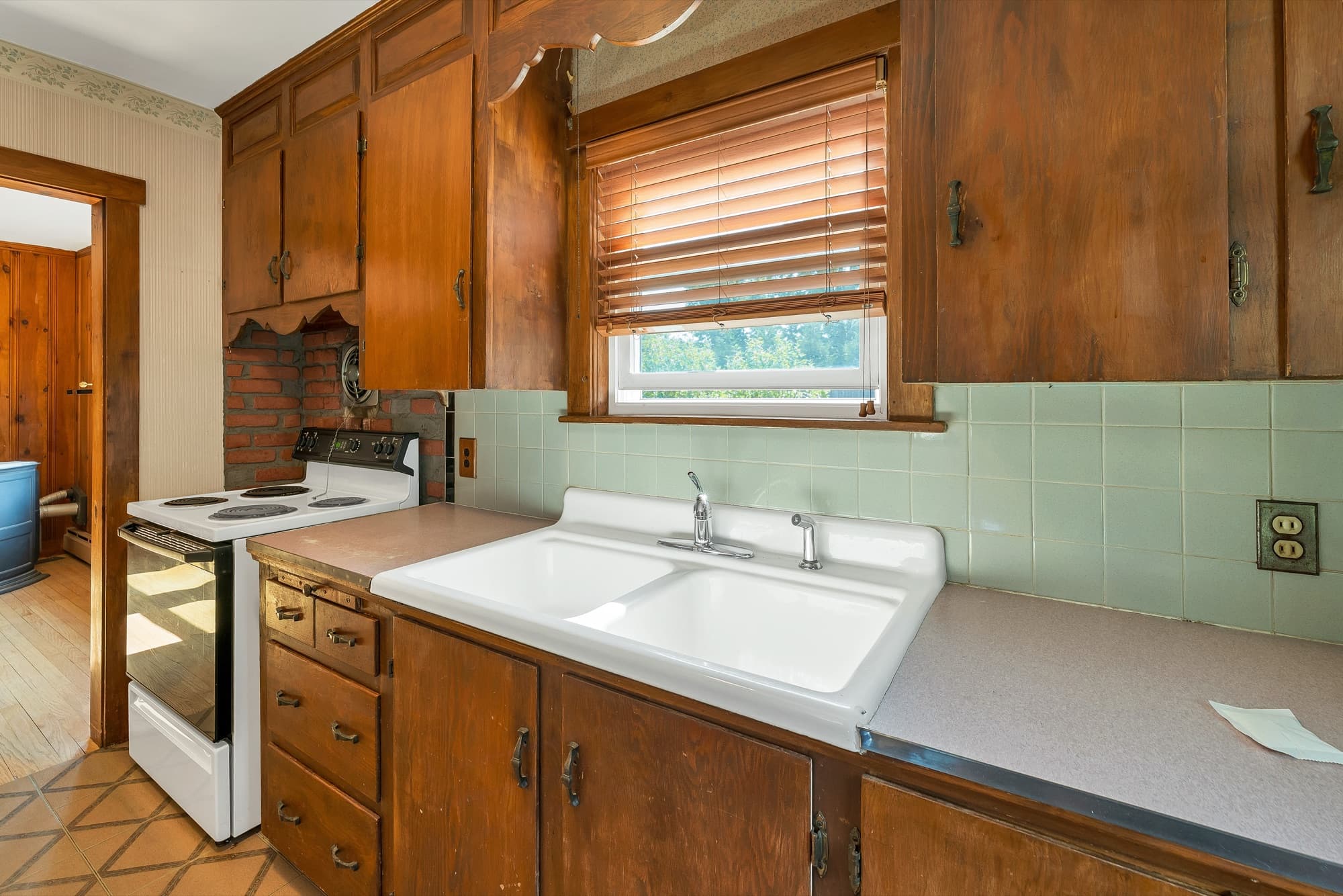 Kitchen sink and counter with wood cabinets and a window over the sink