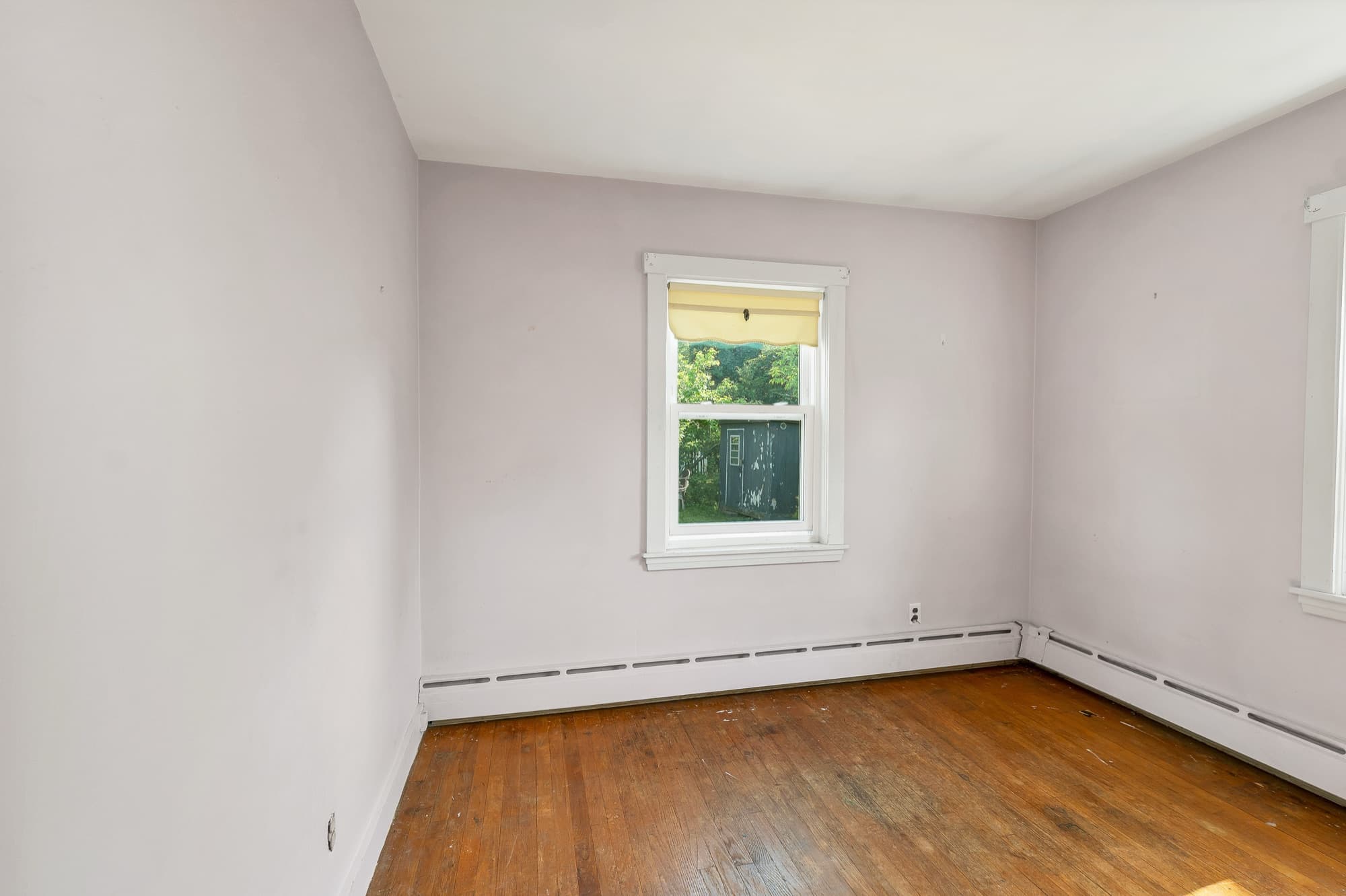 Second bedroom with hardwood floors and a window